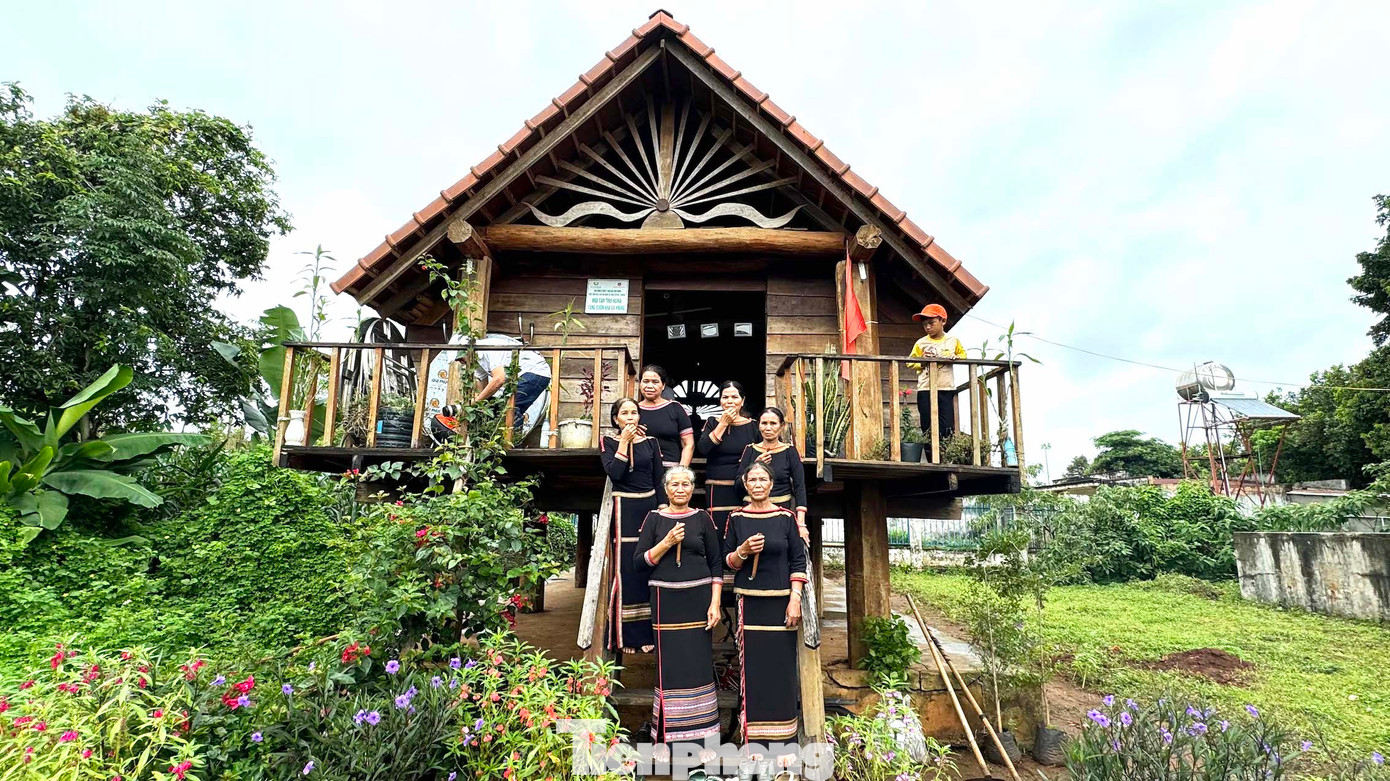 Phụ nữ dân tộc Ê Đê chụp ảnh lưu niệm trước ngôi nhà sàn.