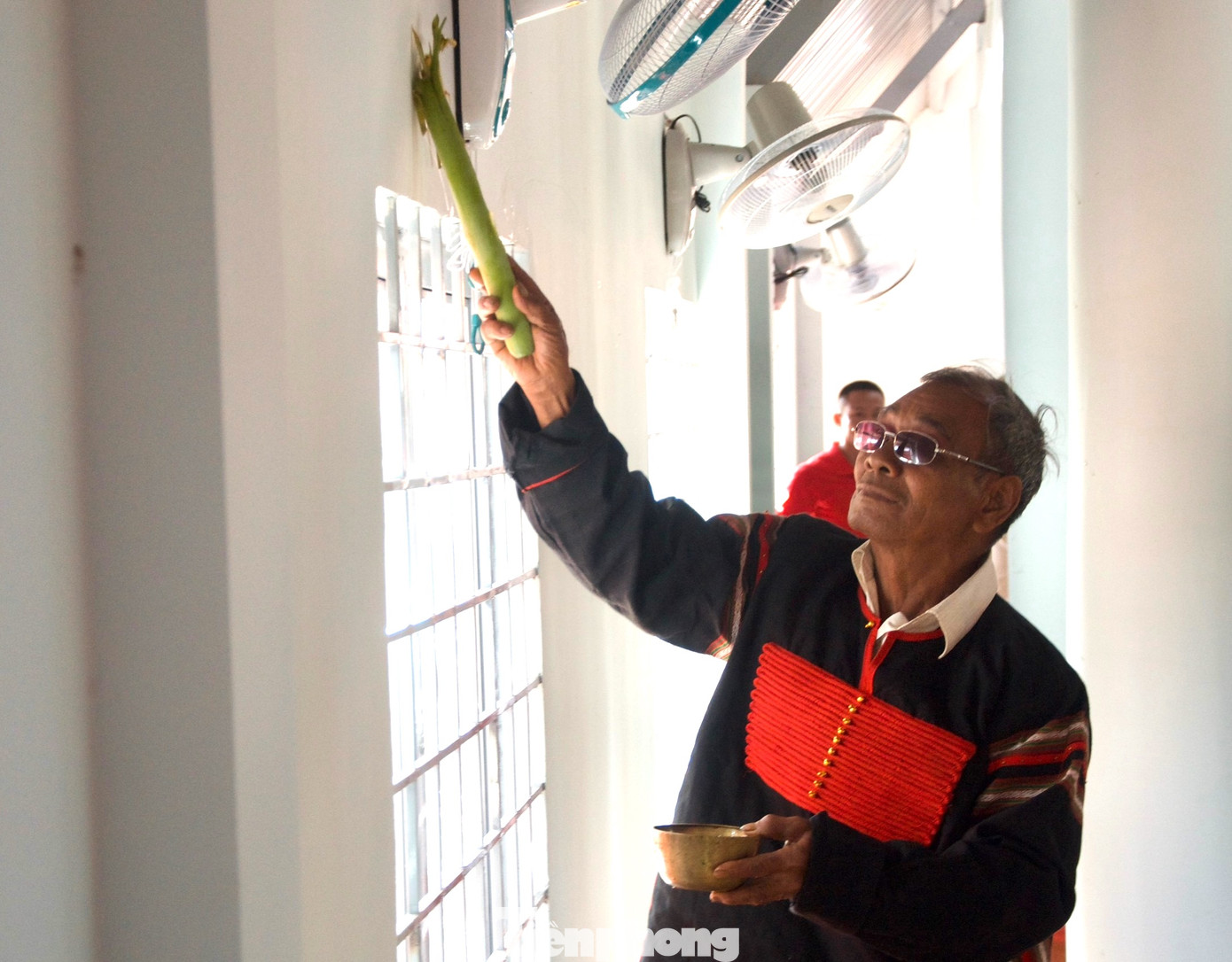 Thầy cúng quét rượu lên tường ngôi nhà