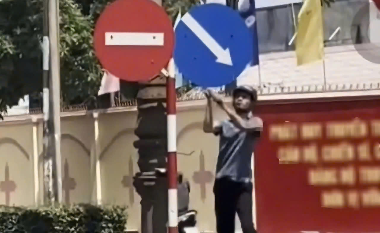 Người đàn ông dùng búa đập biển báo giao thông. Ảnh cắt từ clip