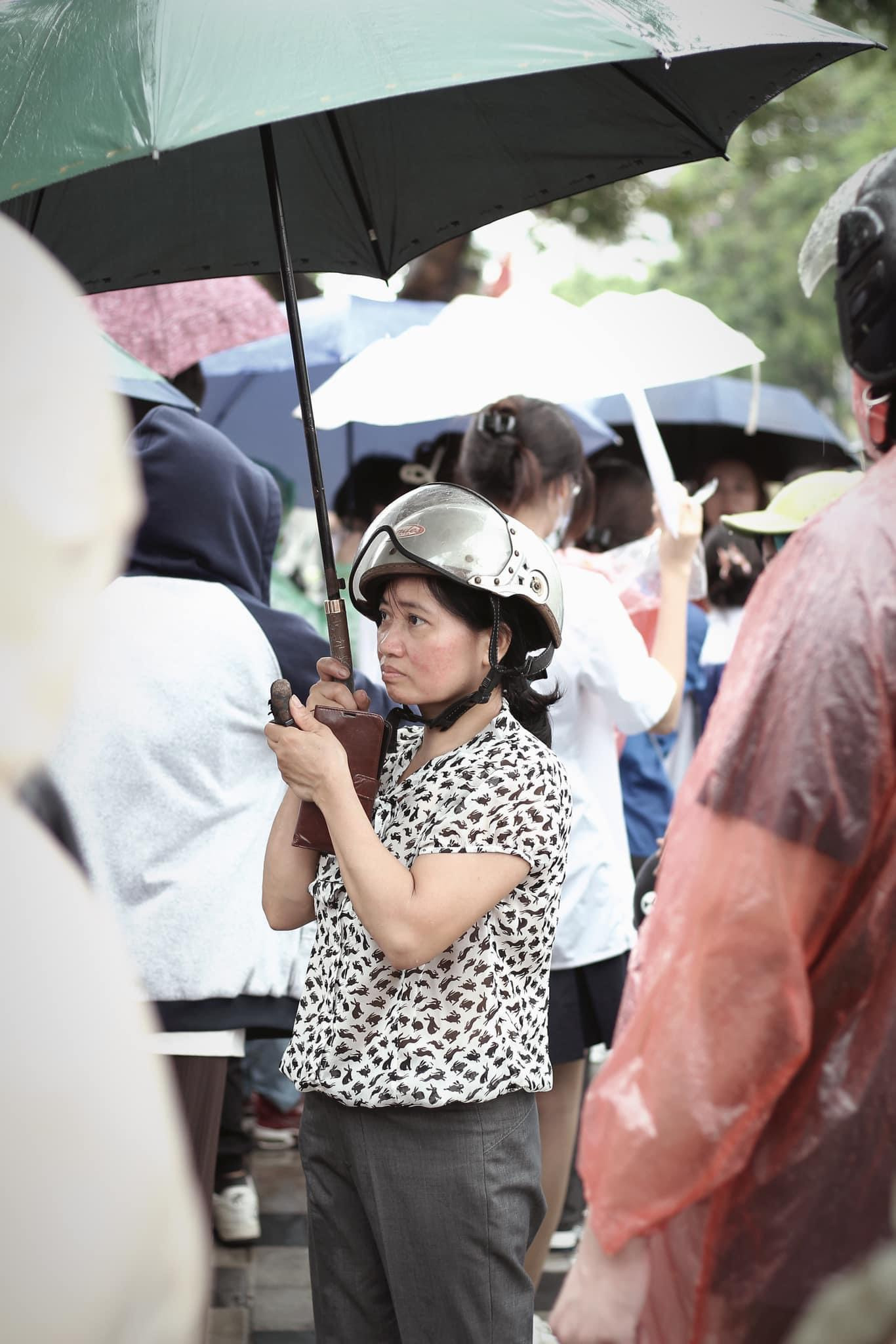 Một phụ huynh không ngại mưa để chờ con hoàn thành xong bài thi. Ảnh: Phan Tiến Mạnh.