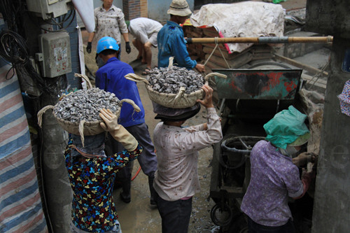 Nhiệm vụ của những người phụ nữ này, là phải đảm bảo máy trộn bê tông có đủ nguyên vật liệu để chạy liên tục.Ảnh: Trường Phong