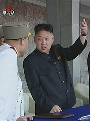 Nhà lãnh đạo Kim Jong-un giơ tay khi đoàn diễu binh đi qua Ảnh: CCTV