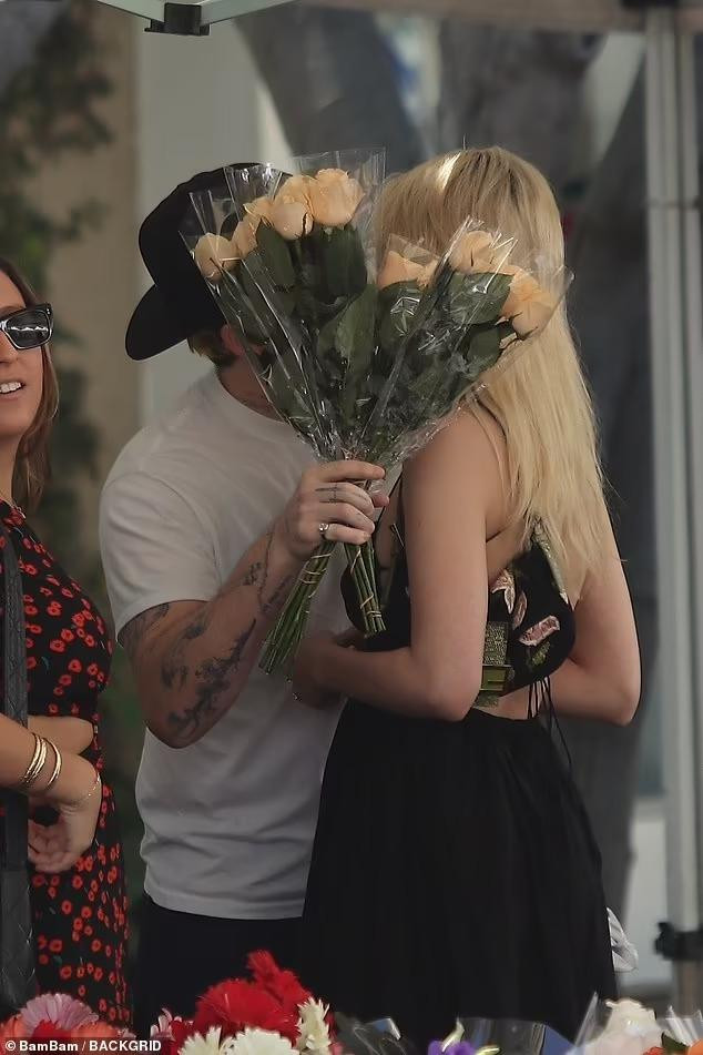 Cặp đôi trao nhau nụ hôn ngọt ngào trước quầy bán hoa.