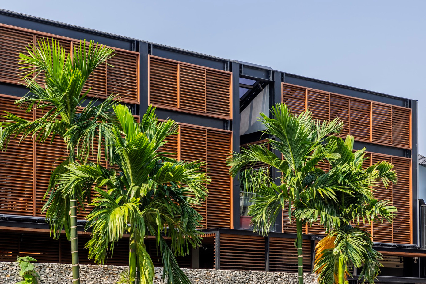 Để đáp ứng nhu cầu của gia chủ, các kiến trúc sư đã triển khai giải pháp thông minh mang tên “Mặt tiền hai lớp”. Cấu trúc này bao gồm hệ thống lam gỗ cách nhiệt (gỗ đã được xử lý nhiệt để tăng độ bền) ở bên ngoài, kết hợp với hệ thống kính trượt bên trong.