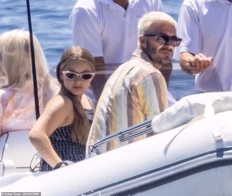 Harper càng lớn càng có nhiều nét giống bố. Cô bé mặc váy hai dây caro và đeo kính râm gọng hồng dễ thương.