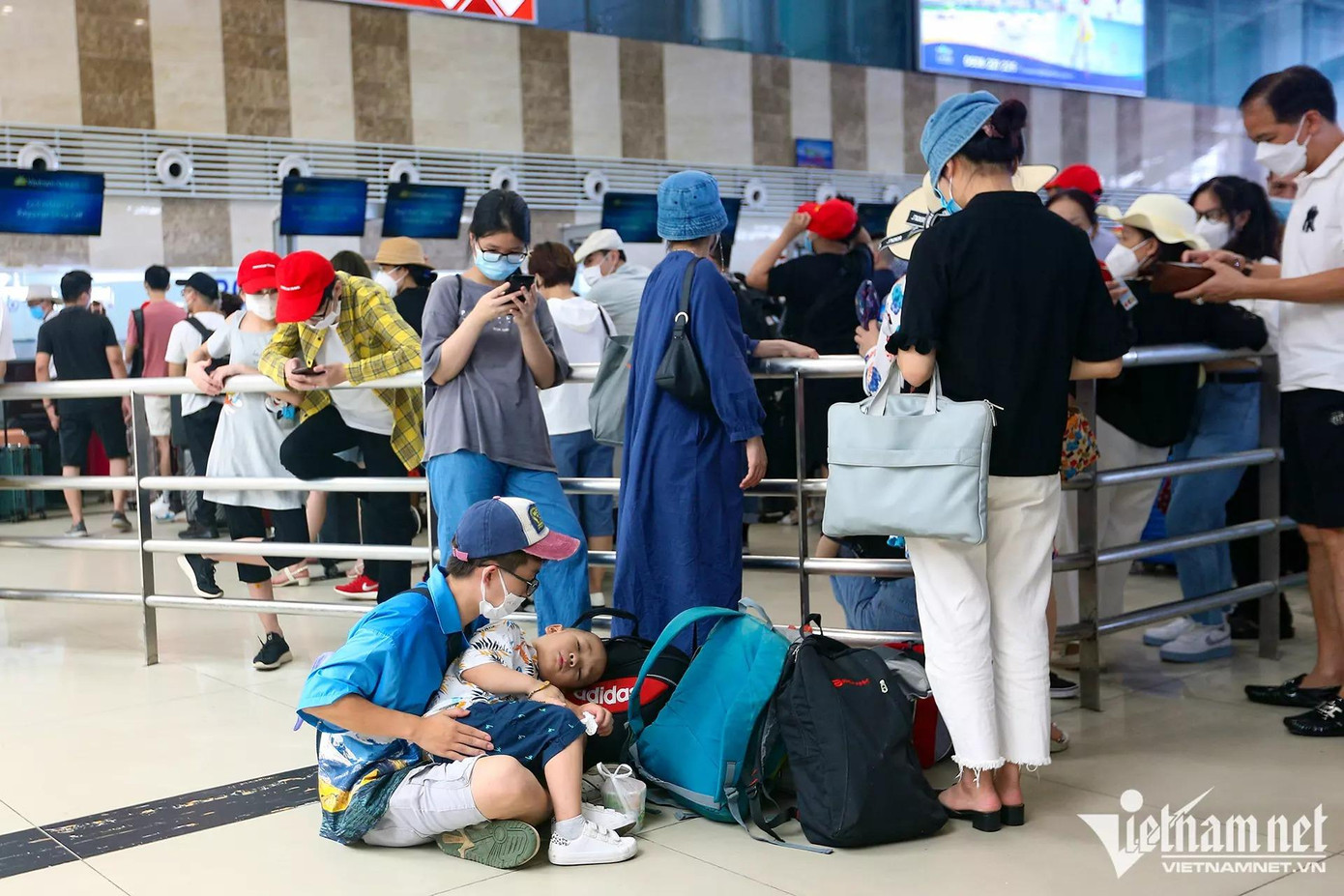 Một gia đình chuẩn bị bay đi du lịch Đà Nẵng từ Hà Nội. Để các con không bị ngột ngạt, bố mẹ của hai em này cho các bé ngồi ngoài trông nhau, còn họ vào xếp hàng đợi làm thủ tục check-in.