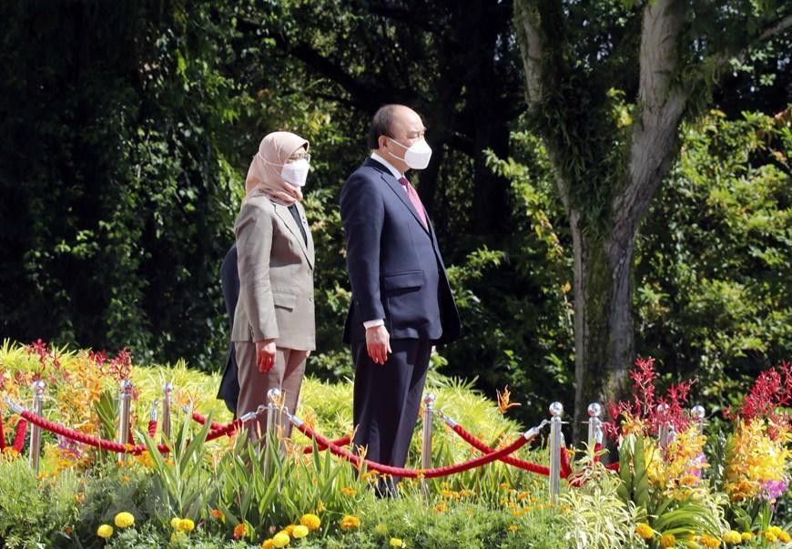 Chủ tịch nước Nguyễn Xuân Phúc và Tổng thống Cộng hòa Singapore Halimah Yacob nghe quân nhạc cử Quốc thiều hai nước. (Ảnh: Thống Nhất/TTXVN)