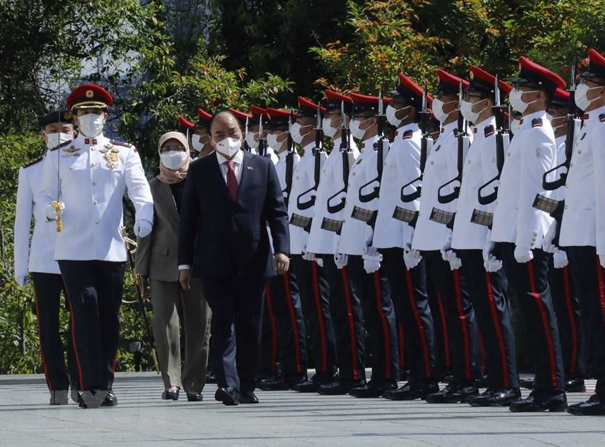 Chủ tịch nước Nguyễn Xuân Phúc và Tổng thống Cộng hòa Singapore Halimah Yacob duyệt đội danh dự. (Ảnh: Thống Nhất/TTXVN)