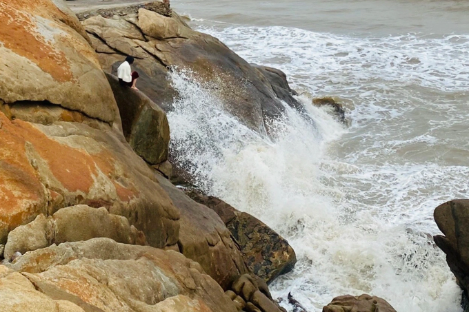 Người phụ nữ ngồi bên mỏm đá bên mép biển ở chân đền Độc Cước, Sầm Sơn, Thanh Hóa (Ảnh: Phòng Cảnh sát PCCC&amp;CNCH)