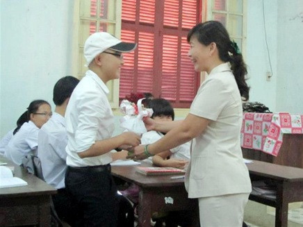 Thùy Miên (đội mũ) trong lần trốn bệnh viện về thăm lớp vì quá nhớ thầy cô, bạn bè. Em được cô giáo tặng hoa động viên tinh thần vượt qua bệnh tật