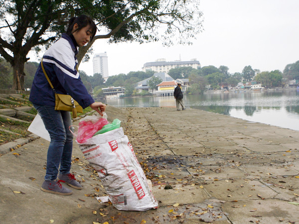 Tình nguyện viên gom túi nilon thả cá chép vứt bừa bãi quanh hồ