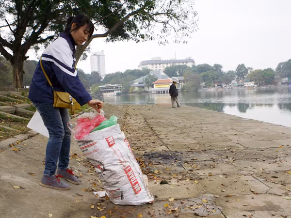 Tình nguyện viên gom túi nilon thả cá chép vứt bừa bãi quanh hồ