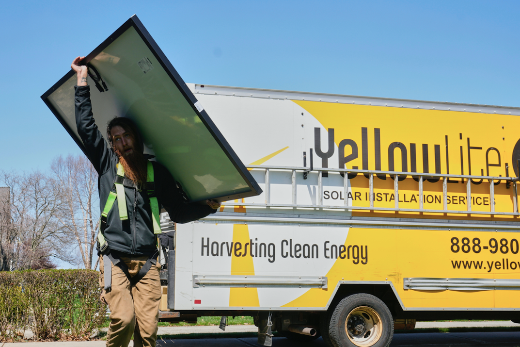 Một nhân viên đang vác tấm pin năng lượng mặt trời để lắp đặt trên mái nhà ở Ohio ngày 16/4. (Ảnh: AP)