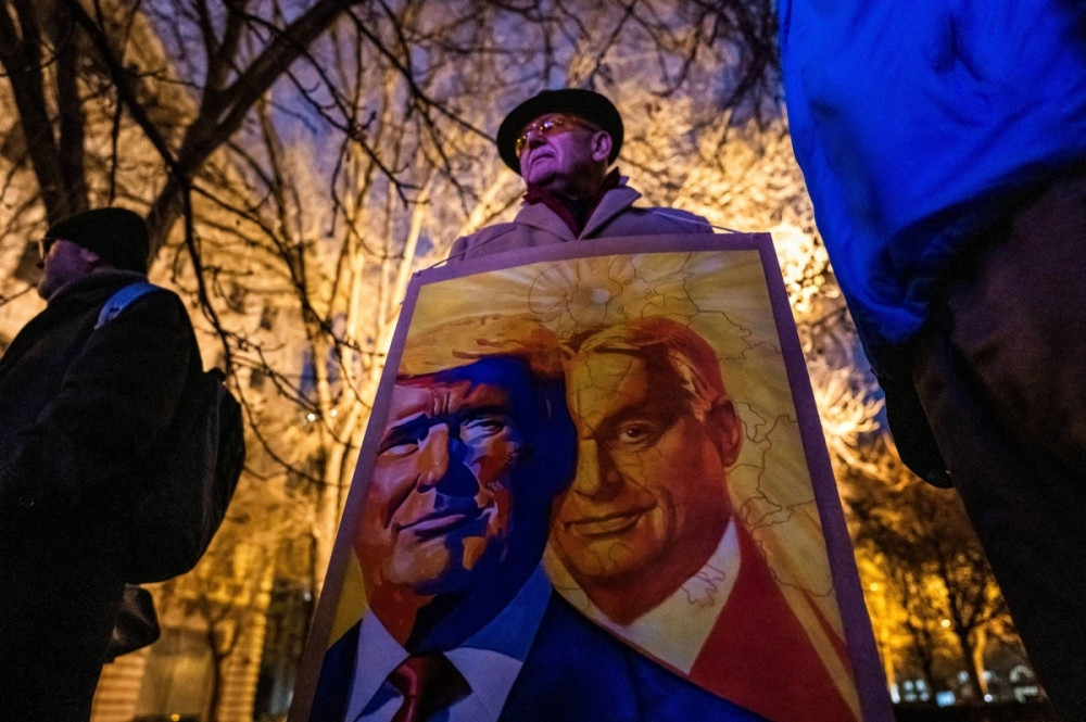 Một người cầm tấm biển có phác họa chân dung Thủ tướng Hungary Viktor Orban và Tổng thống Mỹ Donald Trump tại tiệc nhậm chức được tổ chức bên ngoài Đại sứ quán Mỹ ở Budapest, ngày 20/1. (Ảnh: Reuters) Một người cầm tấm biển có phác họa chân dung Thủ tướng Hungary Viktor Orban và Tổng thống Mỹ Donald Trump tại tiệc nhậm chức được tổ chức bên ngoài Đại sứ quán Mỹ ở Budapest, ngày 20/1. (Ảnh: Reuters)