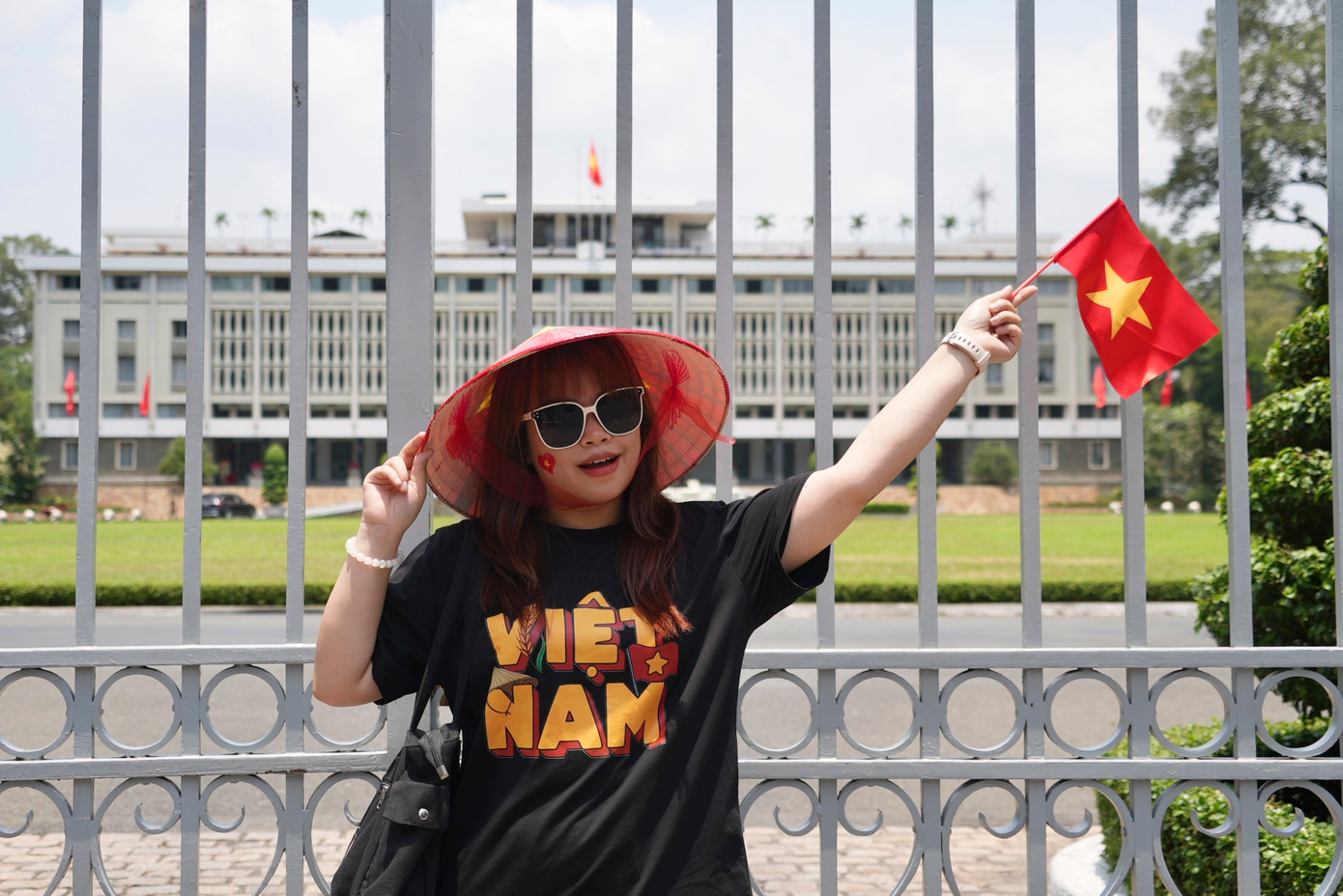 Một cô gái vẫy cờ đỏ sao vàng chụp ảnh trước Dinh Độc Lập. (Ảnh: AP) Một cô gái vẫy cờ đỏ sao vàng chụp ảnh trước Dinh Độc Lập. (Ảnh: AP)