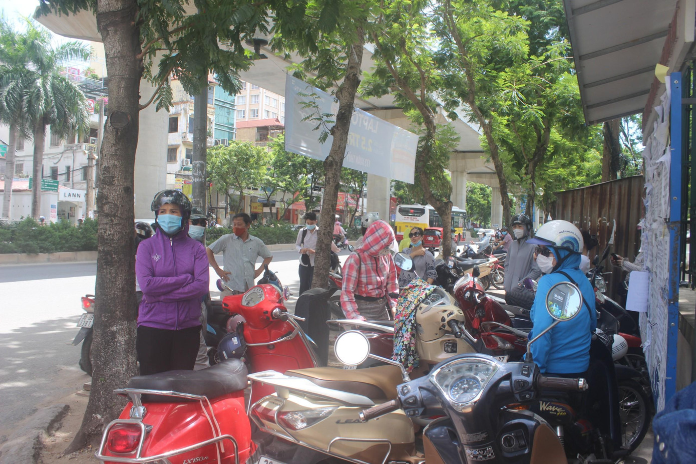 Phụ huynh đội nắng đứng đợi các sĩ tử ngoài cổng trường thi.