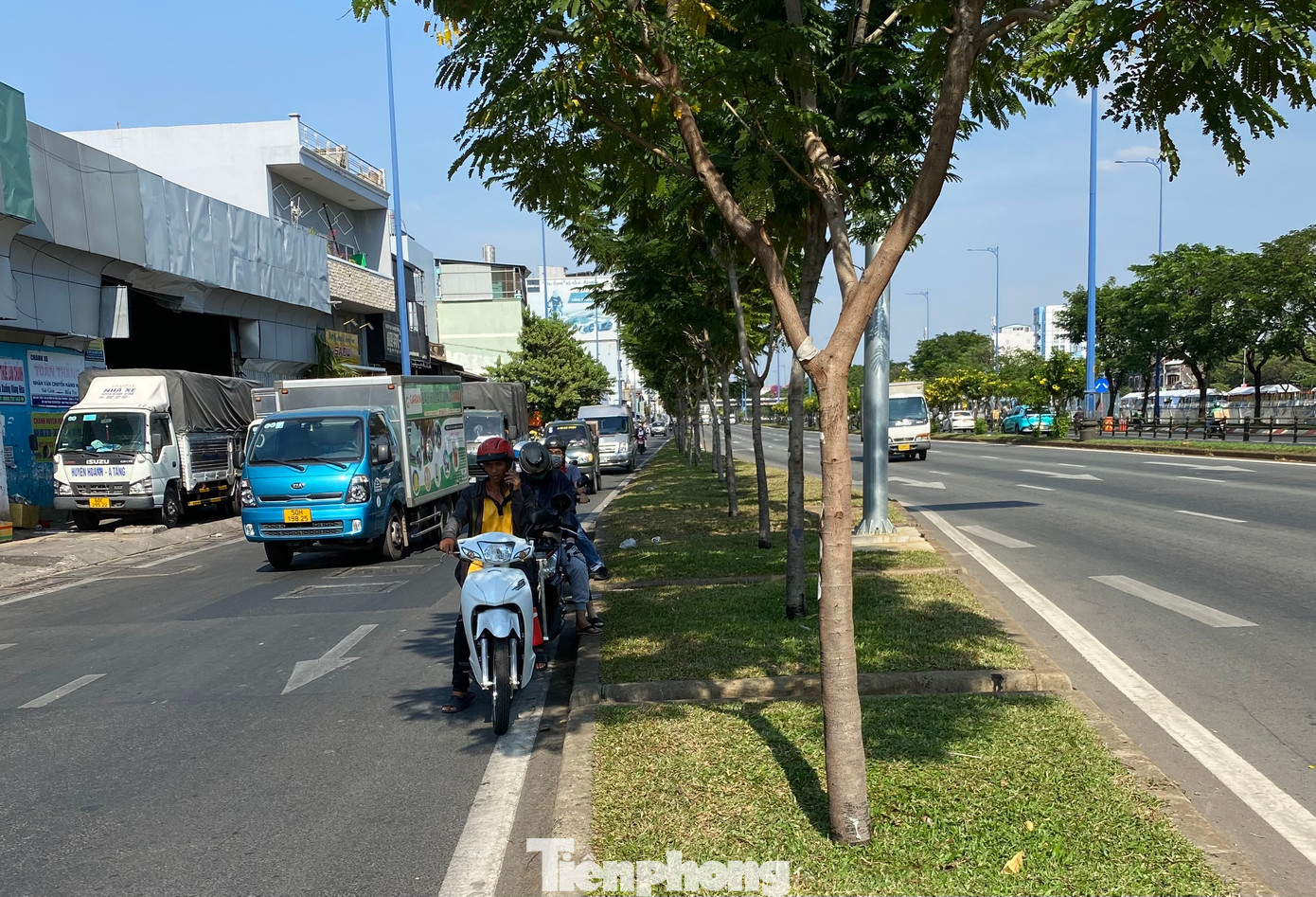 Người dân tận dụng bóng mát từ cây xanh, công trình để tránh nắng khi phải dừng chờ đèn tín hiệu giao thông trên đường Võ Văn Kiệt (quận 5).
