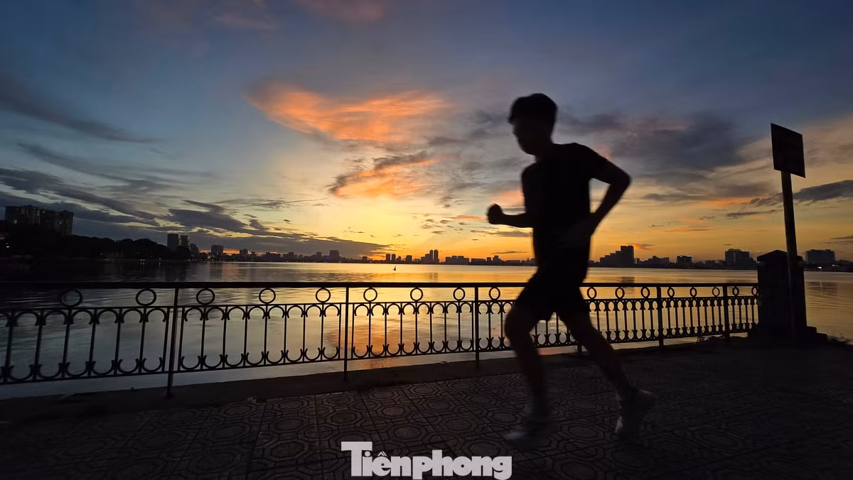 Một người chạy tập thể dục dưới ánh vàng tuyệt đẹp của buổi hoàng hôn Hồ Tây.