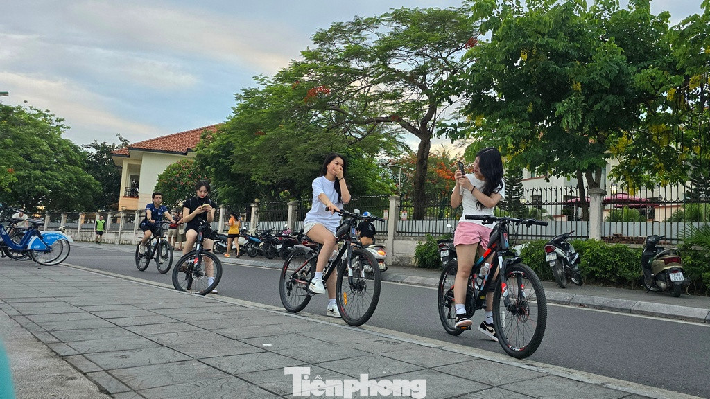 Các bạn trẻ đạp xe tập thể dục dừng chân ngắm vẻ đẹp hoàng hôn khi mặt trời lặn xuống phía bên kia mặt hồ.