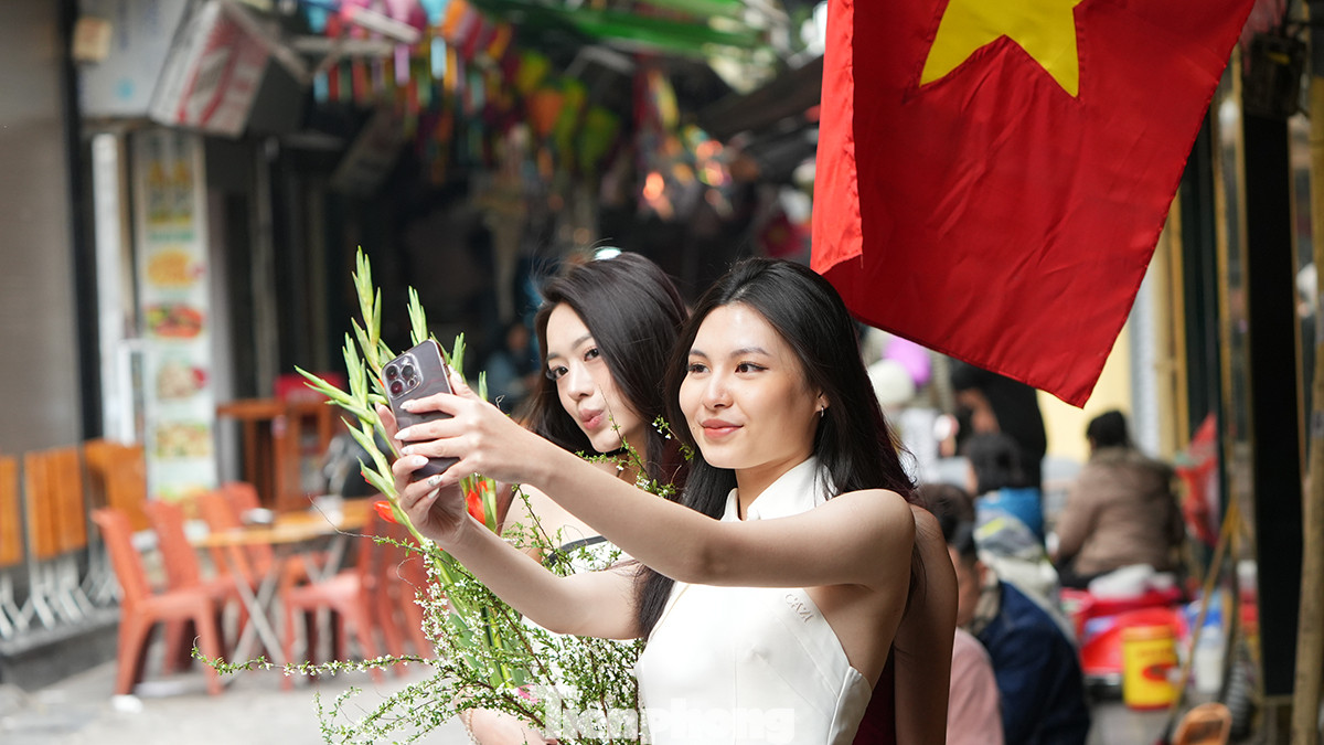 Không quên "check-in" bên quốc kỳ đỏ thắm được treo dọc tuyến phố cổ Hà Nội.