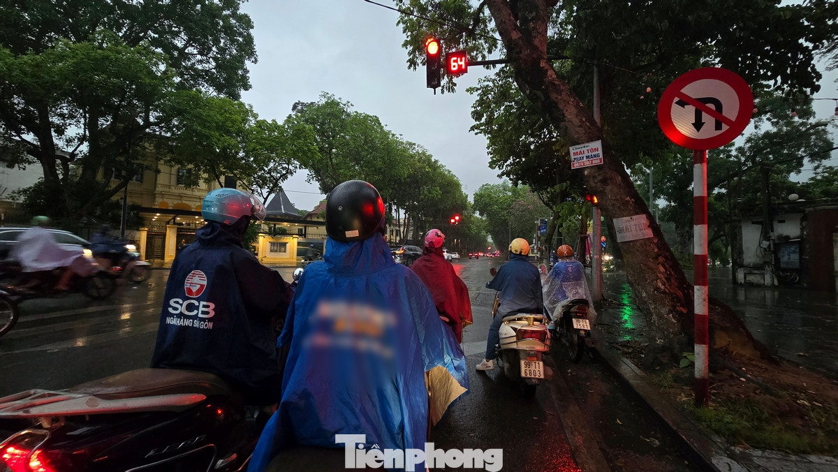 Cơn dông kèm mưa nhỏ khiến đường phố Hà Nội tối đen, giao thông đúng thời điểm đi làm của người dân bị ảnh hưởng.