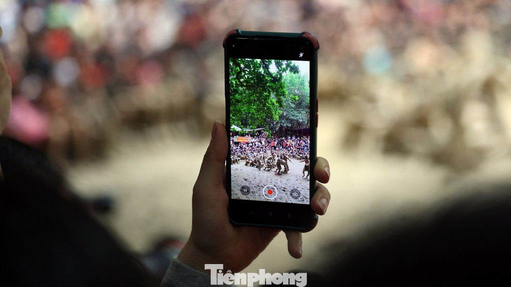 Nhiều người không tiếp cận gần mặt sân mà đứng xa dùng điện thoại quay lại màn tranh giành quả cầu dưới sân đền.