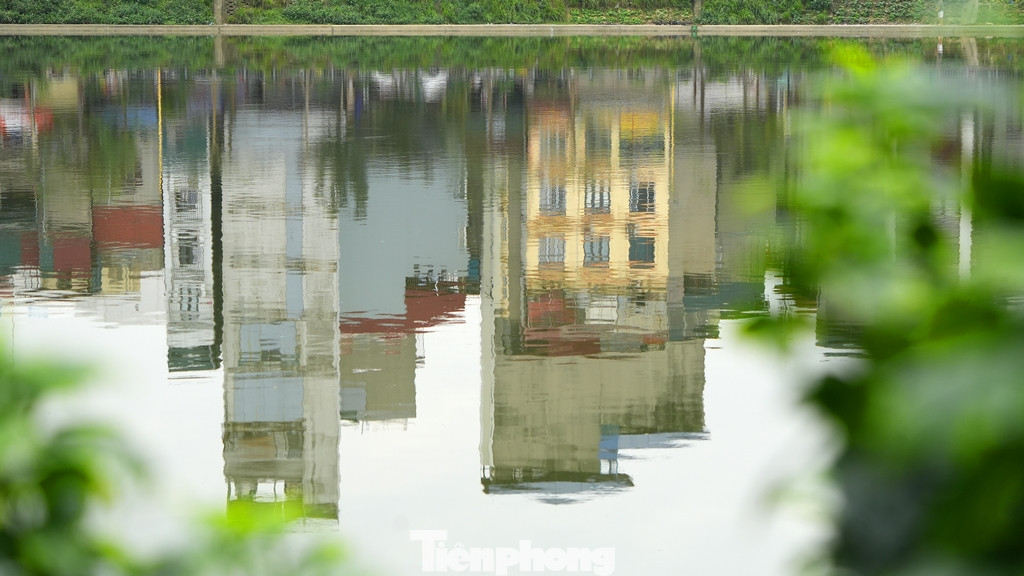 Mặt hồ nước phẳng lặng soi bóng những tòa nhà sau nhiều năm nơi đây là một ao tù, ngập ngụa rác thải và mùi hôi thối.
