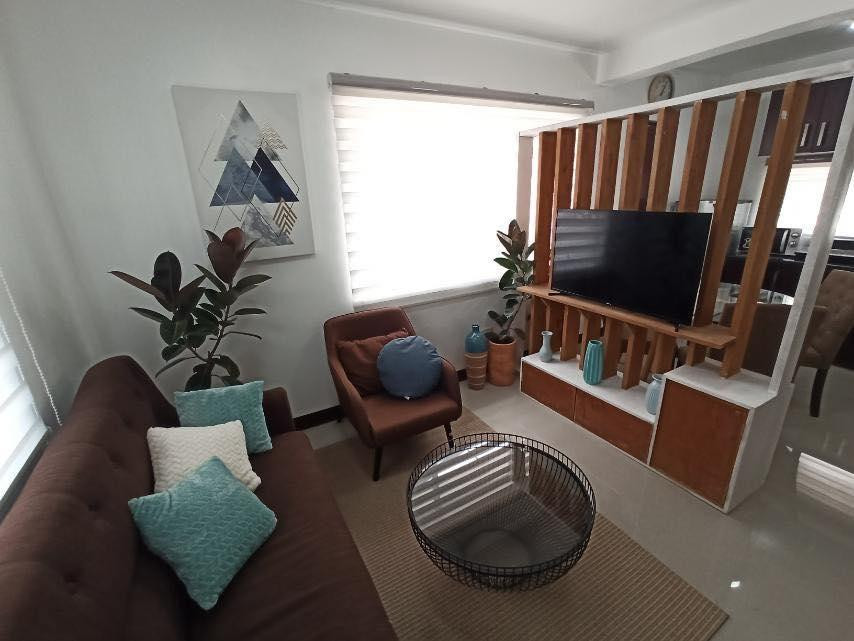 Phòng khách ngôi nhà được ngăn cách với bếp và phòng ăn bằng vách gỗ thoáng và kệ để đồ