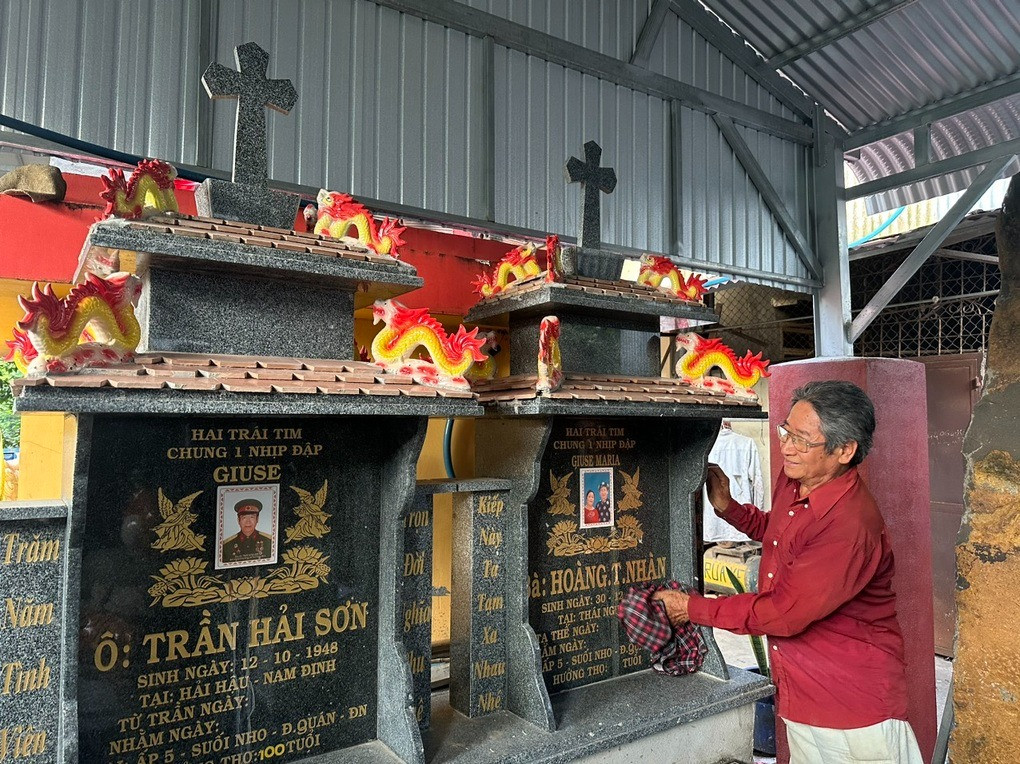 Ông Trần Hải Sơn bên cạnh 2 ngôi mộ của vợ chồng được xây dựng trong khuôn viên của gia đình (Ảnh: Hoàng Bình).