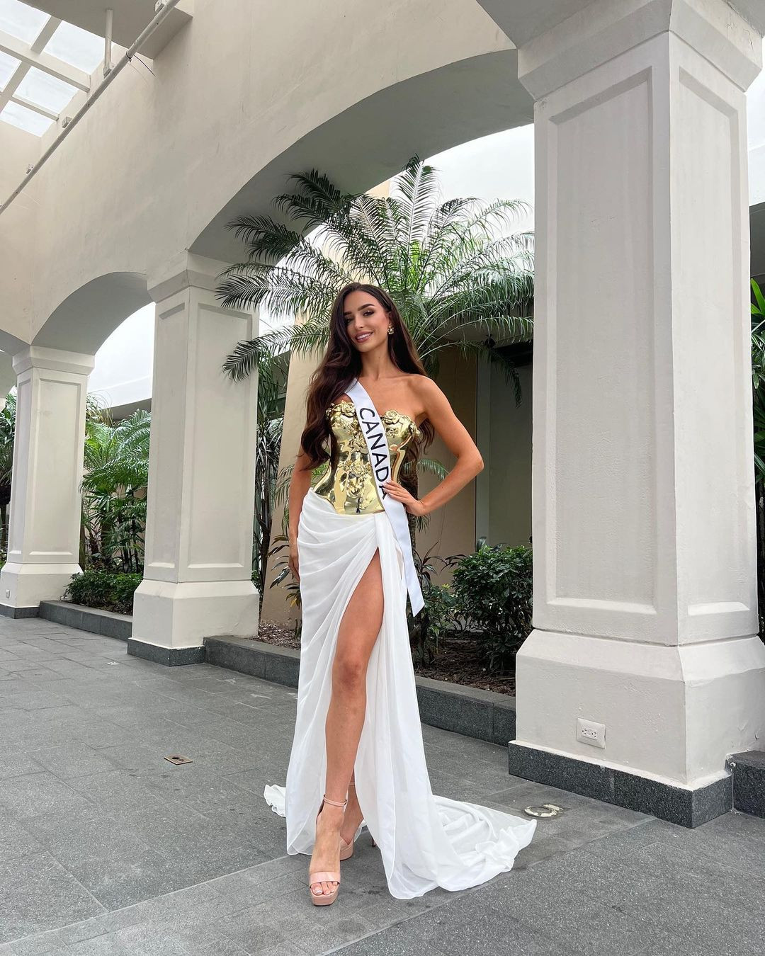 Đại diện Canada khoe chân dài với thiết kế độc đáo, phần thân trên bằng chất liệu kim loại, tông vàng gold. Khán giả nhanh chóng nhận ra bộ váy này từng được Hoa hậu Thùy Tiên diện trước đó tại một sự kiện trong nước.