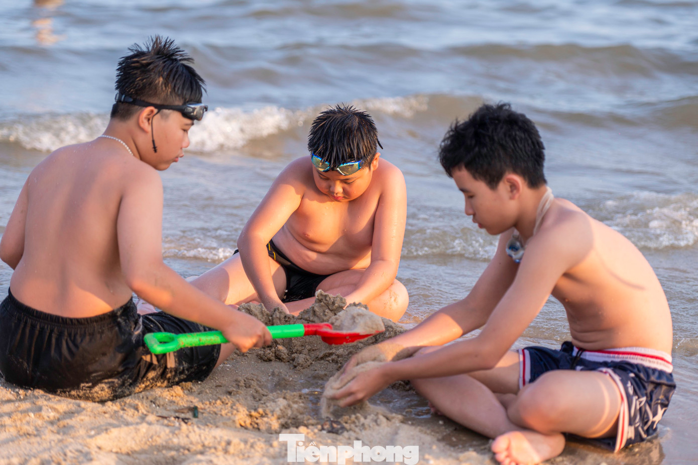 Trẻ em thỏa thích nô đùa bên nhà phao và xây lâu đài cát ngay bên cạnh bờ biển.