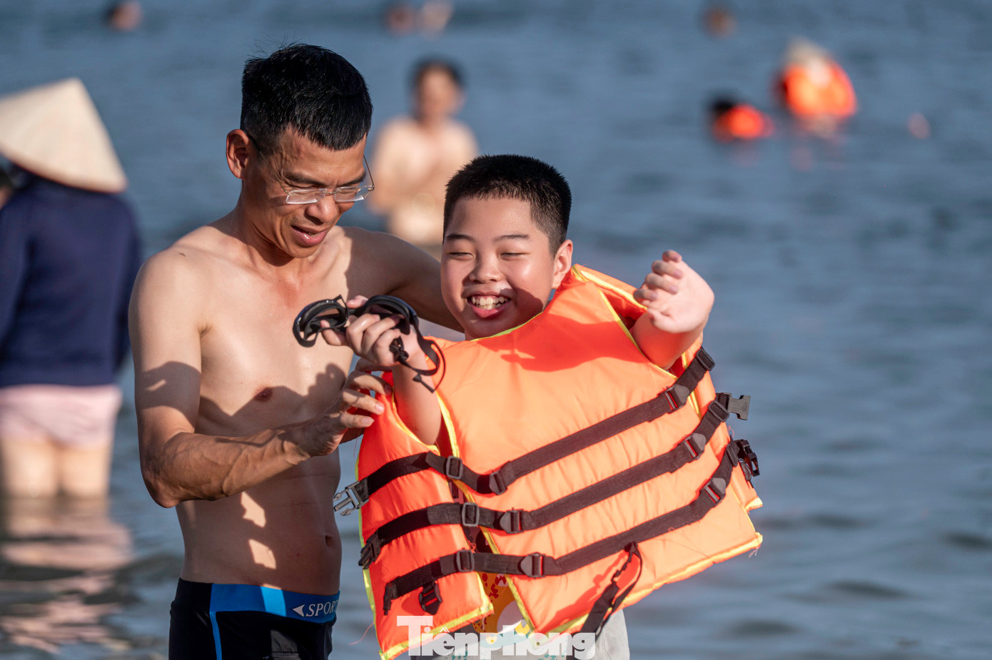 Trẻ nhỏ được bố mẹ mặc áo phao trước khi tắm.