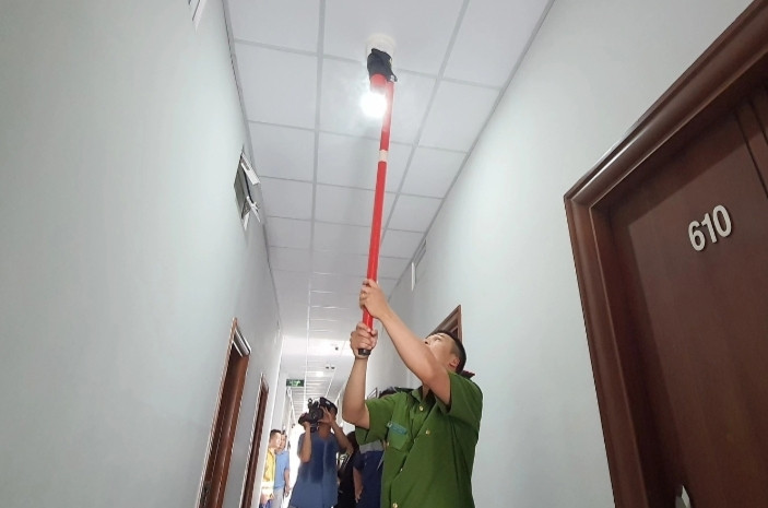 Cảnh sát dùng nguồn nhiệt kiểm tra hệ thống báo cháy tại khu vực hành lang nhà trọ (Ảnh: Nguyễn An).