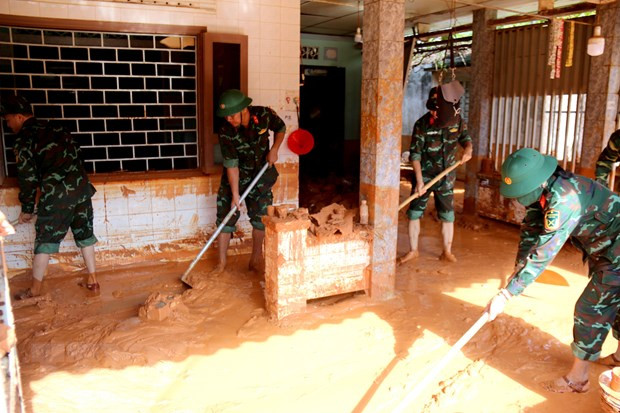 Cán bộ chiến sỹ được huy động để giúp người dân dọn dẹp nhà của và đưa lượng bùn, cát đỏ từ nhà ra ngoài. (Ảnh: Nguyễn Thanh/TTXVN)