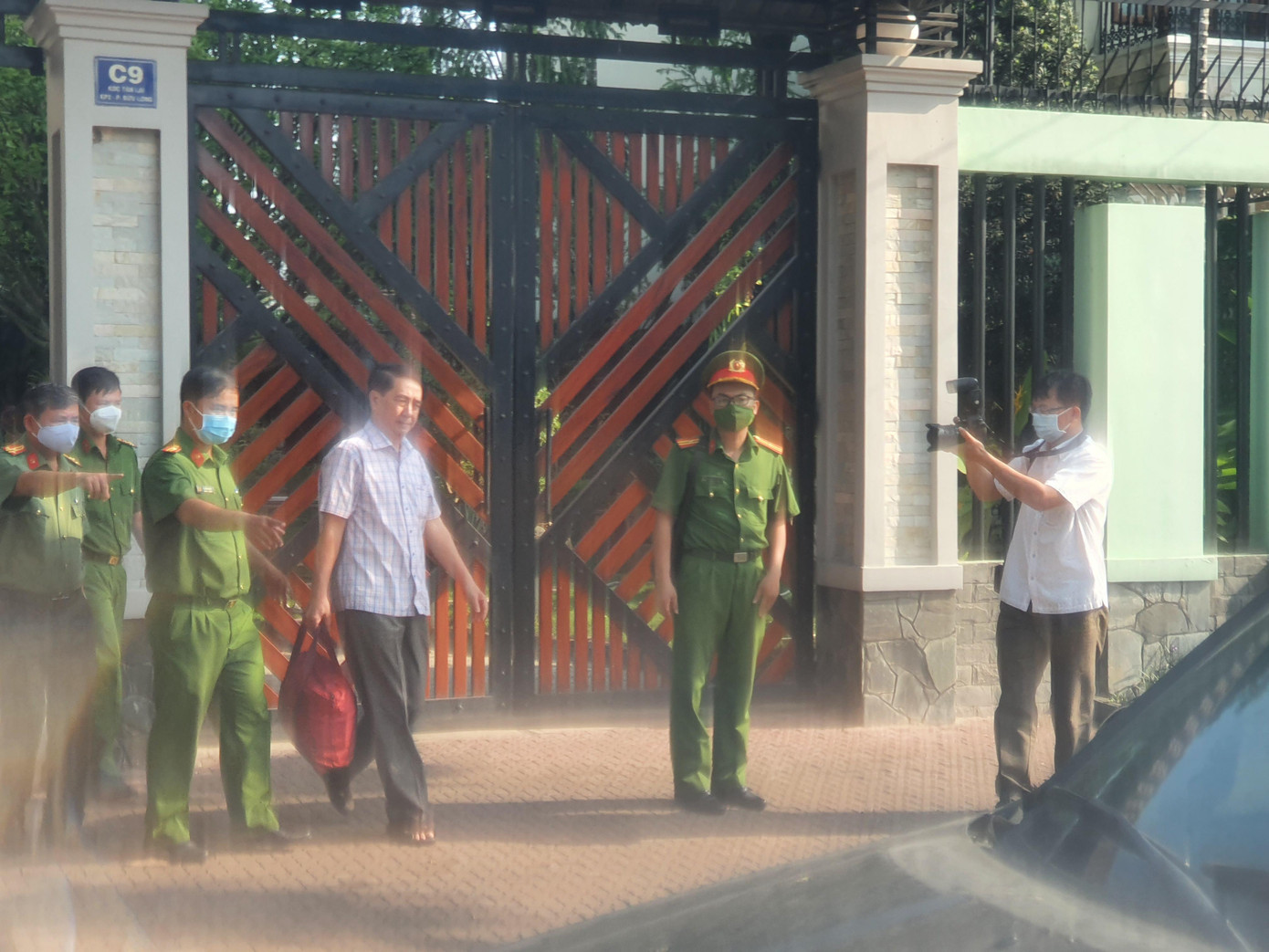 Ông Nguyễn Tấn Long (áo trắng) bị dẫn ra xe
