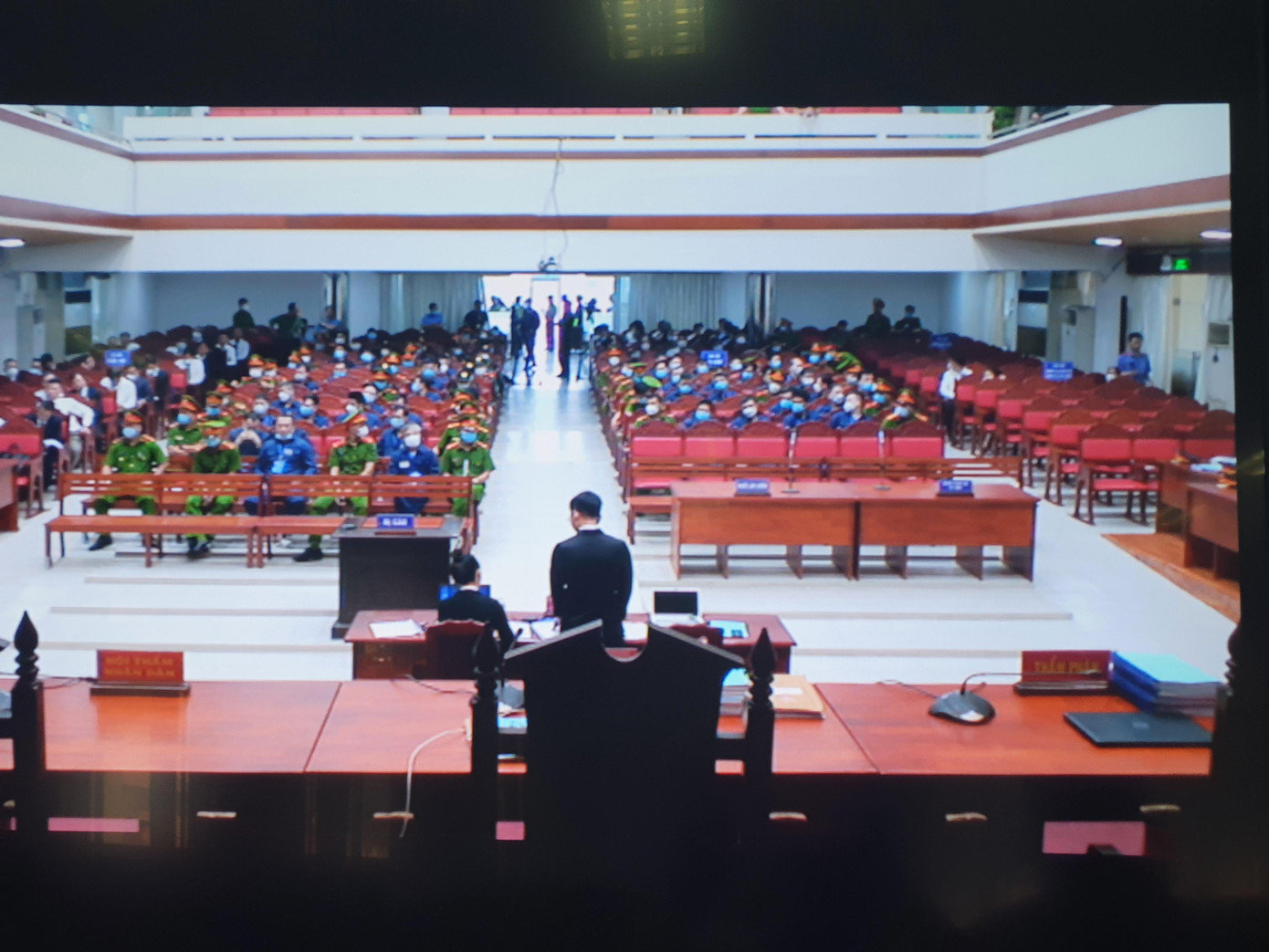 8h30 phiên tòa được khai mạc. Các phóng viên đưa tin được theo dõi phiên tòa qua màn hình.