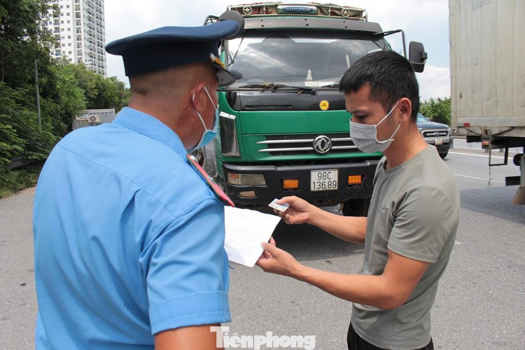 Do không kiểm tra được bằng mã luồng xanh, lực lượng chức năng tại nhiều chốt kiểm soát cửa ngõ trong chiều qua đã chuyển sang kiểm tra giấy xét nghiệm PCR. Nếu giấy còn hiệu lực, lực lượng làm nhiệm vụ sẽ cho xe qua chốt để đảm bảo hành trình, trường hợp PCR hết hạn xe sẽ bị quay đầu. Trong ảnh: Thanh tra giao thông kiểm tra giấy PCR tài xế xe BKS 98C-13689