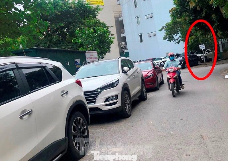 Bãi trông xe thu phí có treo biển công khai (vòng tròn đỏ), kẻ vạch vôi chiếm dụng lòng đường trước tòa nhà VP6 Linh Đàm.
