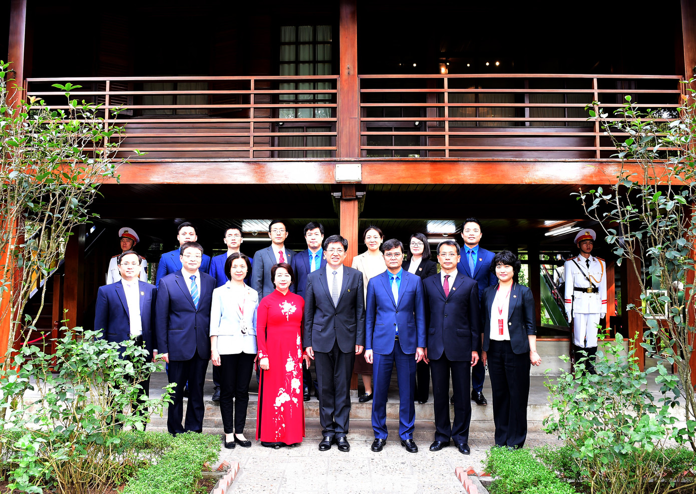 Các đại biểu chụp ảnh lưu niệm bên nhà sàn Bác Hồ tại Khu di tích Chủ tịch Hồ Chí Minh ở Phủ Chủ tịch.