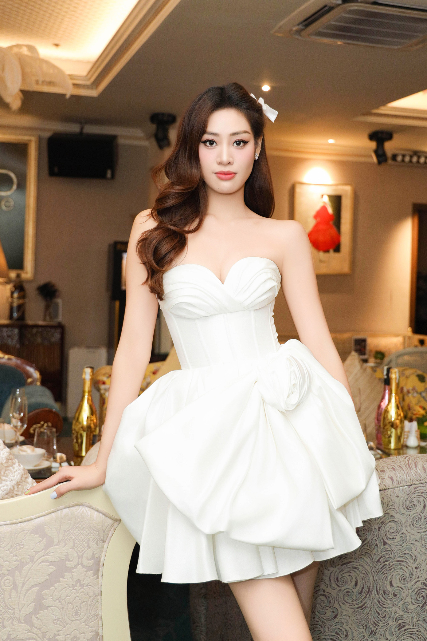 Hoa hậu Hoàn vũ Việt Nam 2019 diện bộ váy cúp ngực màu trắng có kiểu dáng tạo phom 3D yêu kiều. Cô trang điểm nhẹ nhàng trong buổi tiệc.