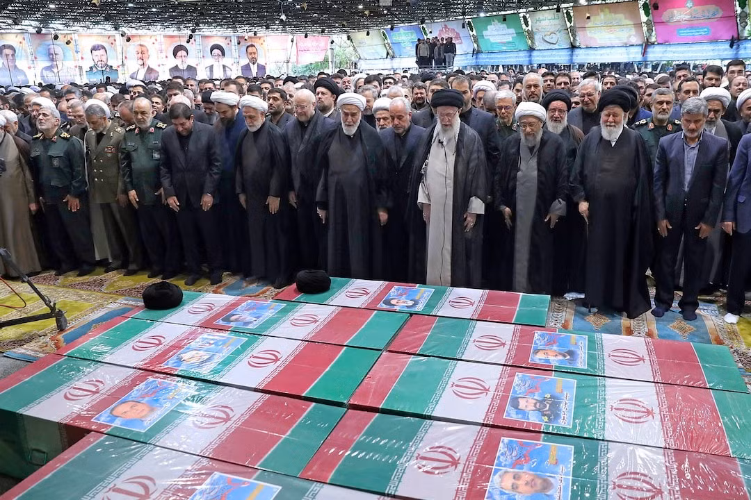 Lãnh tụ tối cao của Iran Ayatollah Ali Khamenei (áo xám) chủ trì nghi thức tang lễ ngày 22/5 ở Tehran. Một chiếc khăn xếp màu đen được đặt trên linh cữu của ông Raisi. Ảnh: Reuters