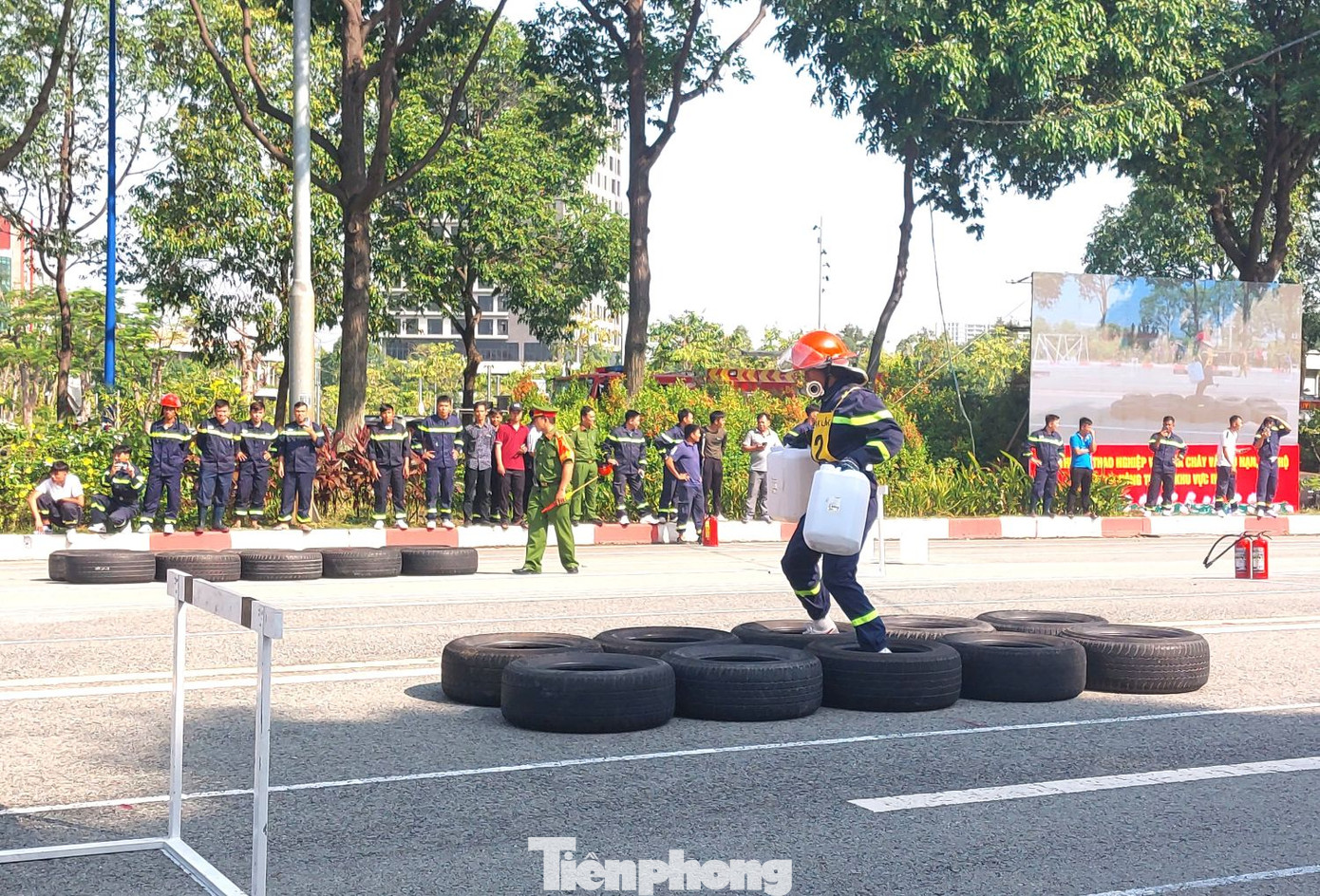 Các vận động viên thực hiện thao tác xách hai thùng nước chạy qua vật cản.