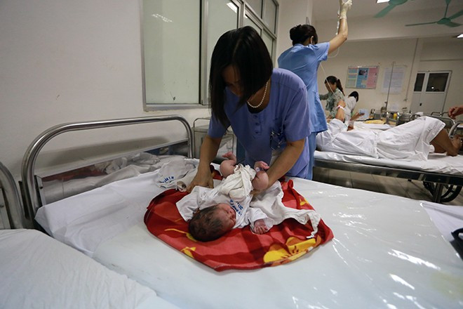 Nữ hộ lý trưởng Nguyễn Thị Vinh thay tã và mặc quần áo cho bé Dung 