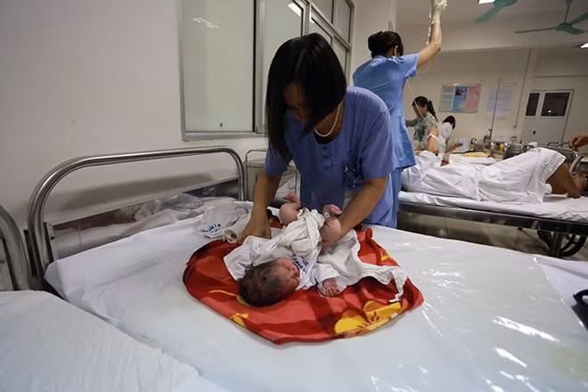 Nữ hộ lý trưởng Nguyễn Thị Vinh thay tã và mặc quần áo cho bé Dung 