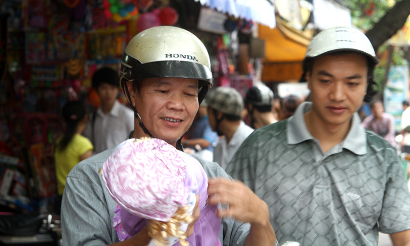 Niềm vui của một phụ huynh khi mua được món quà là cô búp bê để tặng bé trong ngày tết thiếu nhi trên phố Lương Văn Can