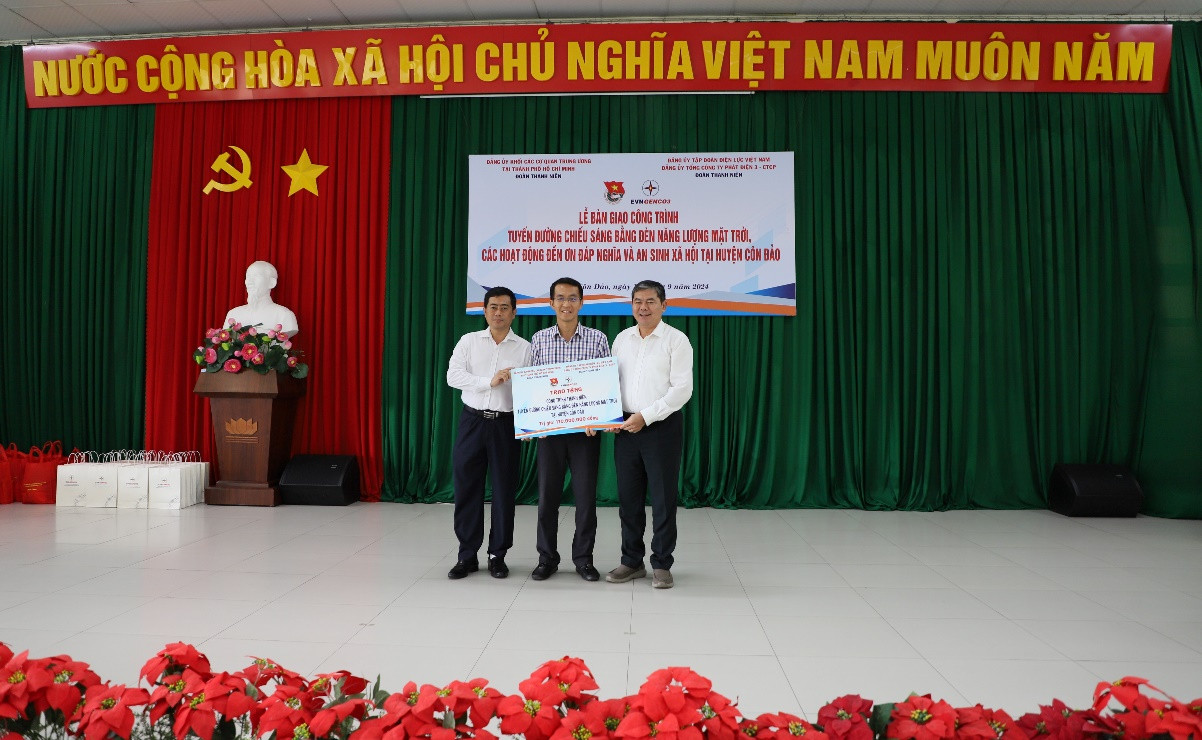 Đồng chí Võ Văn Yên – Phó bí thư thường trực Đảng ủy Khối (bìa bên phải) và đồng chí Hồ Văn Trung – Đảng ủy viên EVNGENCO3 (bìa bên trái) trao bảng tượng trưng bàn giao công trình tuyến đường chiếu sáng bằng năng lượng mặt trời cho đại diện lãnh đạo Huyện Côn Đảo