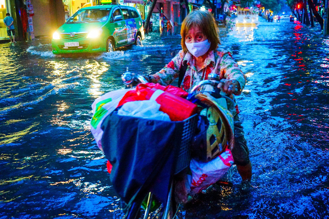 Một cụ bà phải bì bõm di chuyển qua điểm ngập trên đường Nguyễn Thái Bình, Quận 1.