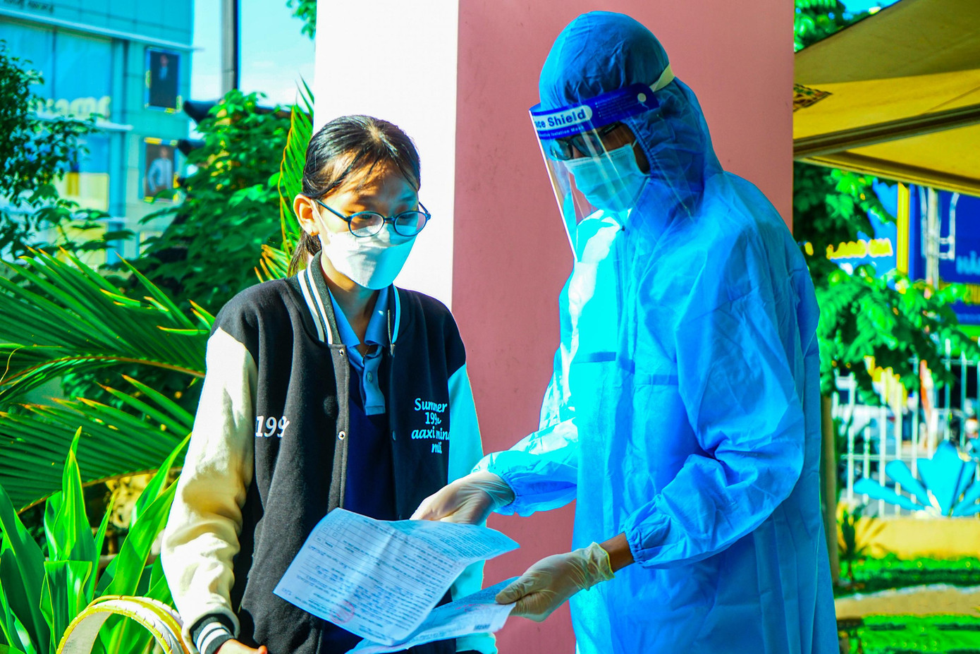 Tình nguyện viên thuộc CLB Sức Trẻ Tình Nguyện, quận Gò Vấp kiểm tra giấy xác nhận tiêm cho học sinh trước khi vào khu vực tiêm.