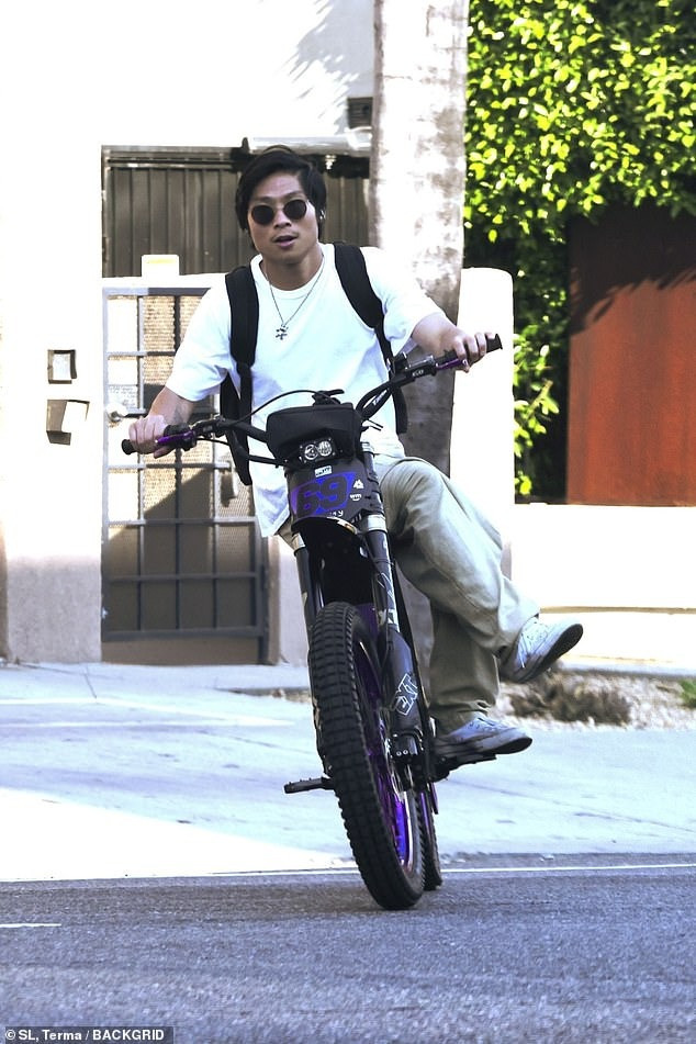 Pax Thiên ngồi bắt chân một bên, không đội mũ bảo hiểm khi lái xe đạp điện vào ngày 11/7. Ảnh: BackGrid.