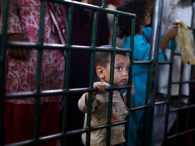 Một em bé Pakistan đứng bên cạnh chị gái đợi đến lượt nhận gạo từ thiện ở Beri Imam, Islamabad